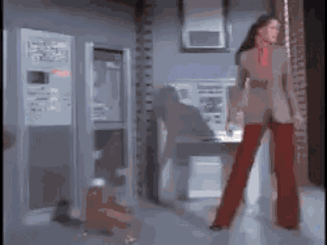 a woman in red pants is standing in a hallway in front of a machine .