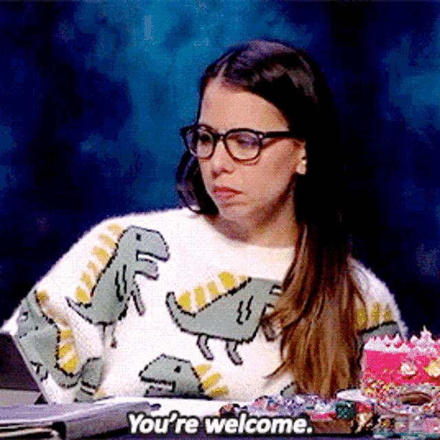 a woman wearing glasses and a sweater with dinosaurs on it says you 're welcome