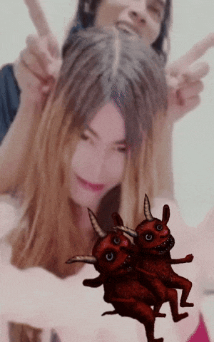 a man and a woman are posing for a picture with devils dancing in front of them
