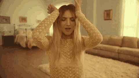a woman in a white dress is dancing in a living room .