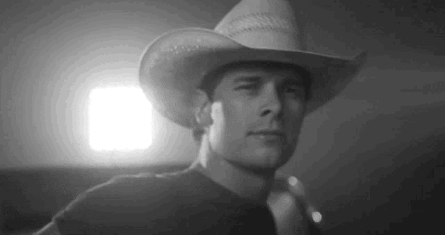 a man wearing a cowboy hat is standing in front of a light .