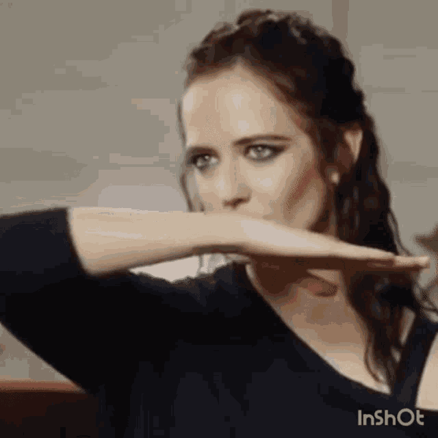 a woman is covering her mouth with her hand while wearing a black shirt .