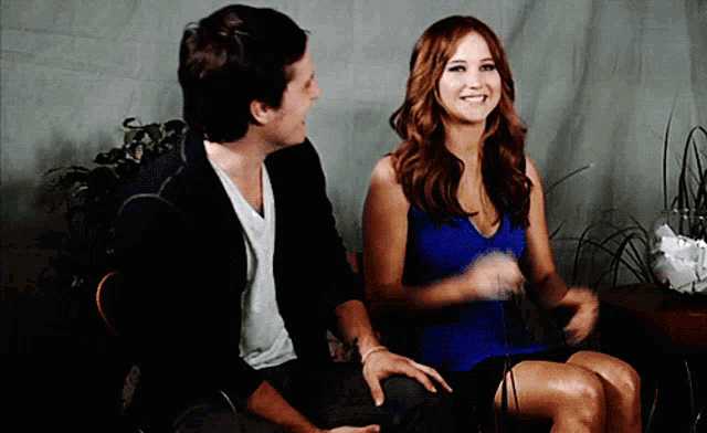 a man and a woman are sitting next to each other smiling