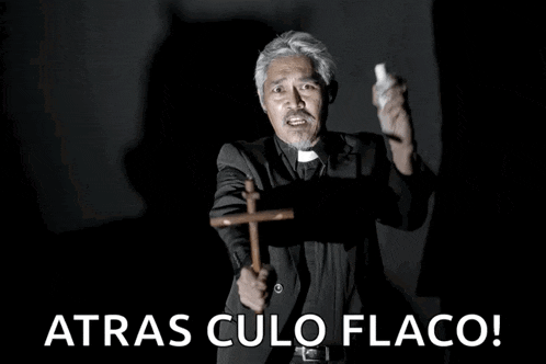 a man in a suit is holding a wooden cross with the words atras culo flaco behind him