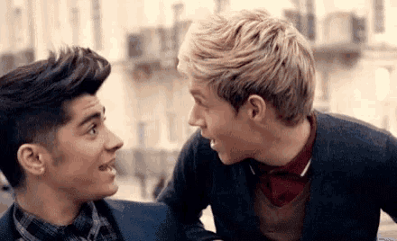 two young men are looking at each other and smiling while sitting next to each other .