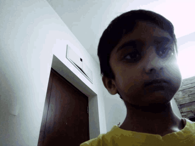 a boy in a yellow shirt looks at the camera
