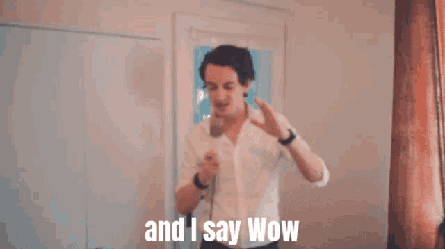 a man holding a microphone with the words " and i say wow " above him