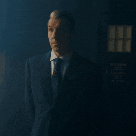 a man in a suit and tie is standing in front of a police box