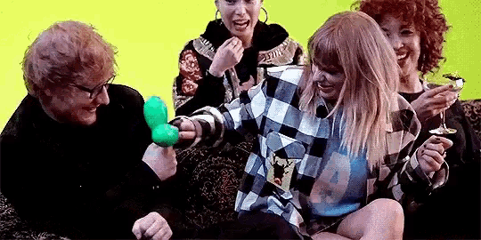 a group of people are sitting on a couch playing with balloons .