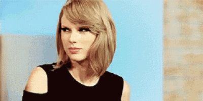 taylor swift is making a funny face while wearing a black dress .