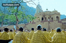 a group of people are sitting in front of a temple .
