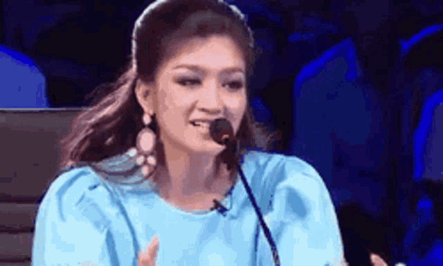 a woman is sitting in front of a microphone and smiling .