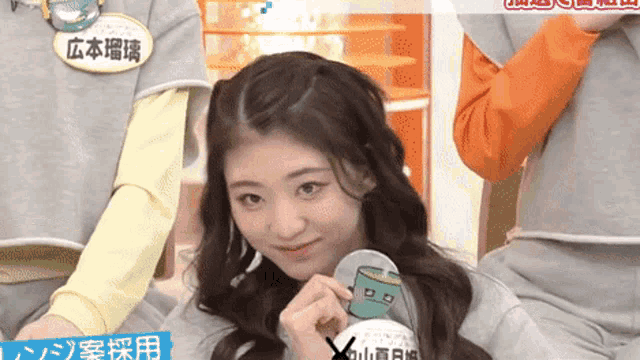a girl with chinese writing on her shirt is holding a cup