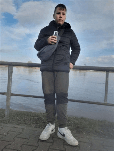 a boy in a black jacket holds a cell phone