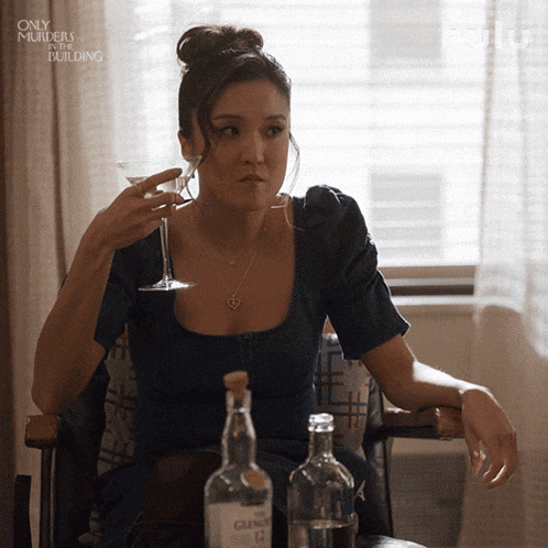 a woman sitting in a chair drinking a martini from a glass