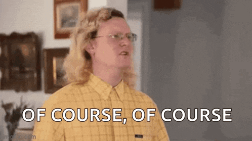 a man with long blonde hair and glasses is standing in a living room .