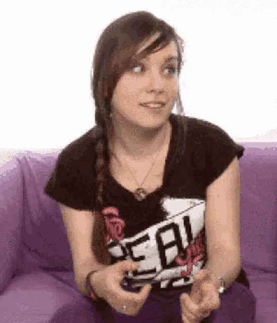 a young woman is sitting on a purple couch making a funny face .