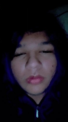 a close up of a person 's face with purple hair and their eyes closed