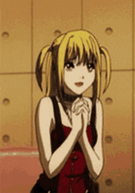 a girl with blonde hair and pigtails is sitting in a chair with her hands folded in front of her face .