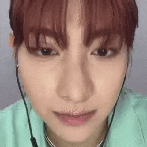 a close up of a woman 's face wearing headphones and a green shirt .