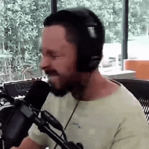 a man wearing headphones is talking into a microphone .