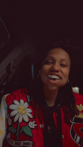 a woman wearing a red jacket with a flower and a peace sign on it