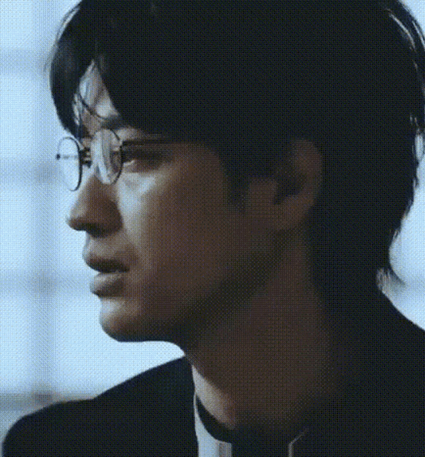 a man wearing glasses and a suit is crying .