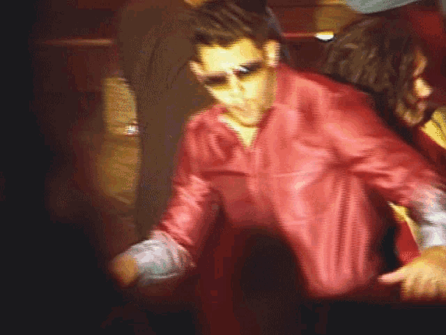 a man in a red leather jacket and sunglasses is dancing