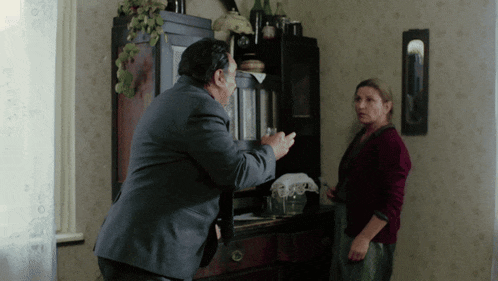 a man in a suit is talking to a woman in a red shirt