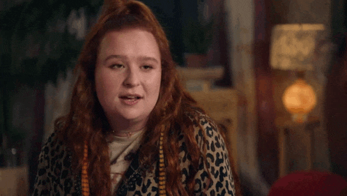 a woman with red hair is wearing a leopard print sweater and a necklace .