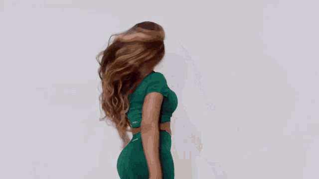 a woman with long hair is wearing a green top and green pants