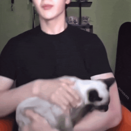 a man in a black shirt is petting a cat