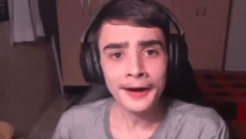 a young man wearing headphones is making a funny face while sitting in a chair .