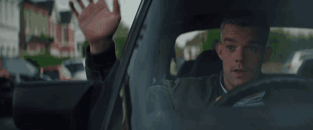 a man is driving a car and looking out of the window