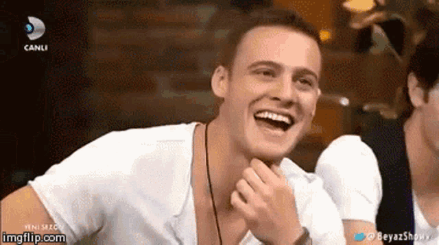 a man in a white shirt is laughing in front of a screen that says canli