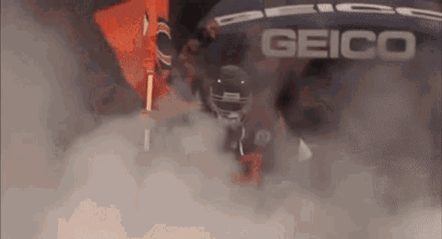 a football player is walking through a cloud of smoke while wearing a helmet .
