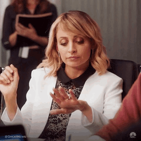 a woman in a white jacket is sitting at a table holding a pen .