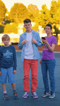 a boy wearing a hansen 's shirt stands next to a woman