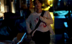 a woman in a white sweater is standing in a dark room at night .