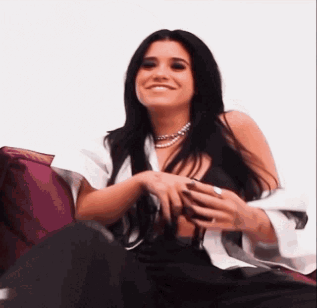 a woman with long black hair is sitting on a purple couch smiling