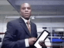 a man in a suit and tie is holding a piece of paper in a boxing ring .