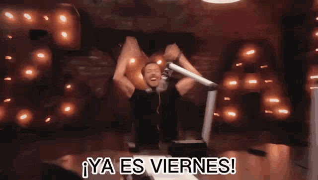 a man in front of a microphone with the words ya es viernes on the bottom