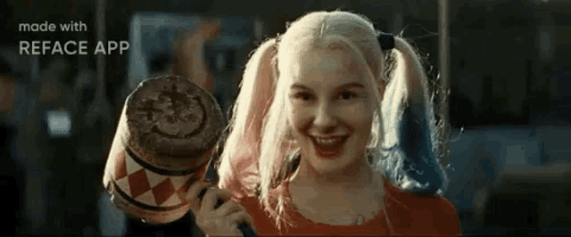 a woman in a harley quinn costume is holding a mallet and smiling .