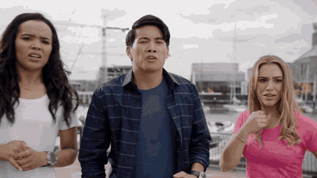 a man in a plaid shirt stands between two women in pink shirts
