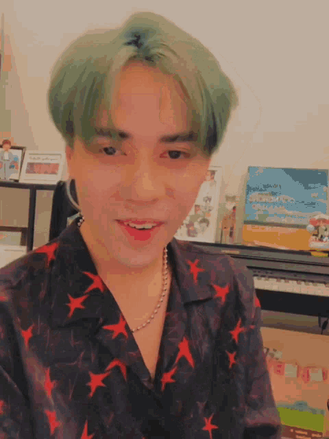 a young man with green hair is wearing a shirt with red stars