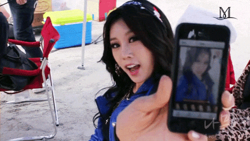 a woman takes a picture of herself with a cell phone with the letter m on it