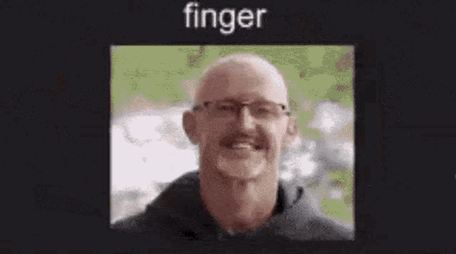 a bald man with glasses and a mustache is smiling in a blurry photo .