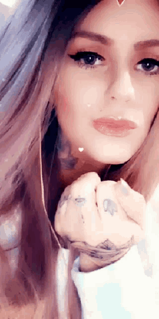 a close up of a woman 's face with a tattoo on her hand