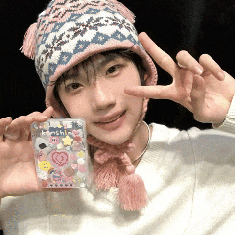 a person wearing a hat and scarf is holding a clear case that says kenshine