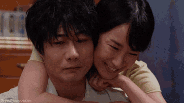 a man and a woman are hugging each other with the website drivelmangooz.com visible in the corner